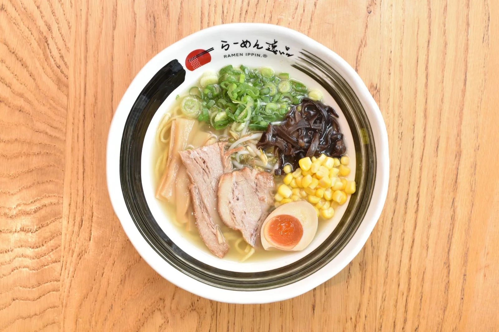 Ramen bowl viewed from above on a light wooden table