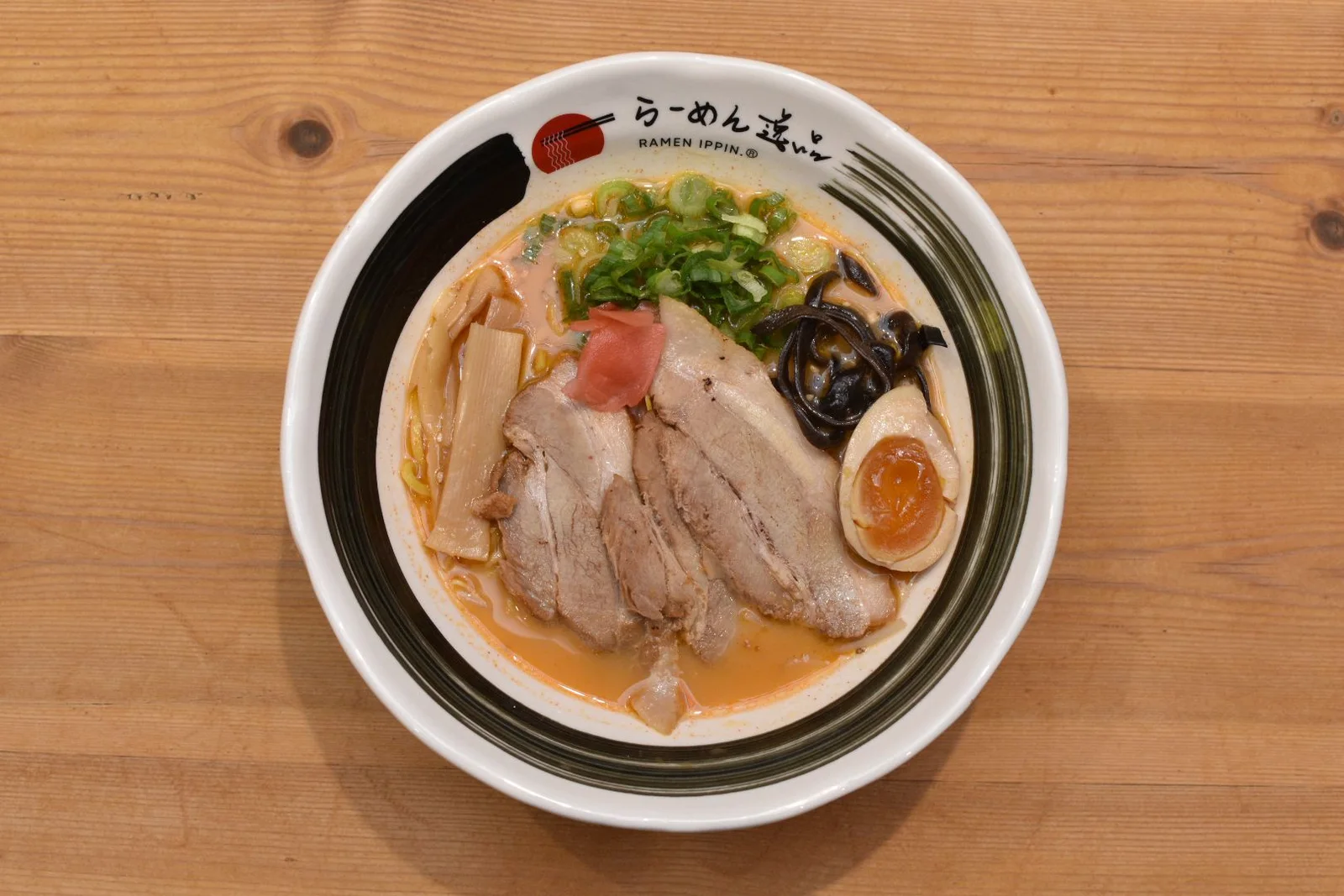 Ramen bowl viewed from above on a warm wooden table